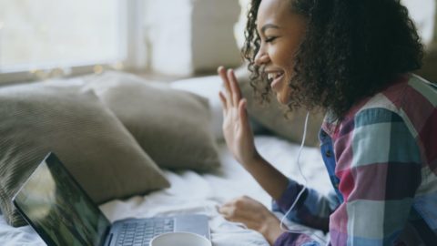 Woman of Color on Virtual Meeting over laptop waving hello