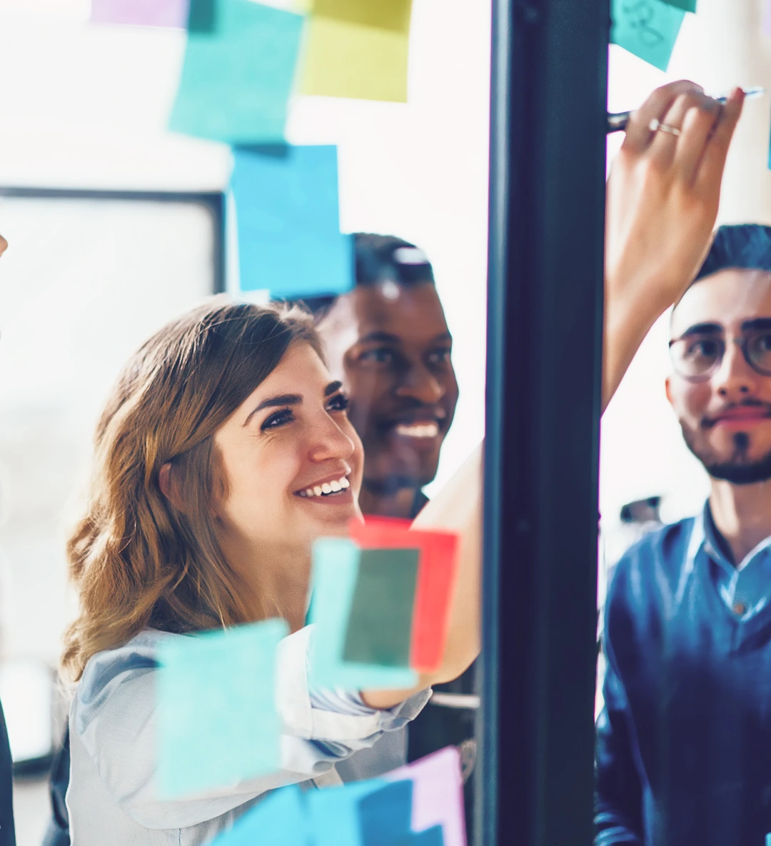A woman writes on sticky notes to discuss business objectives with her team